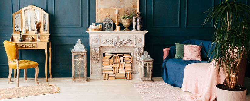 Blue,grey paneled back wall with classic white fireplace used as book storage and lots of decorative items